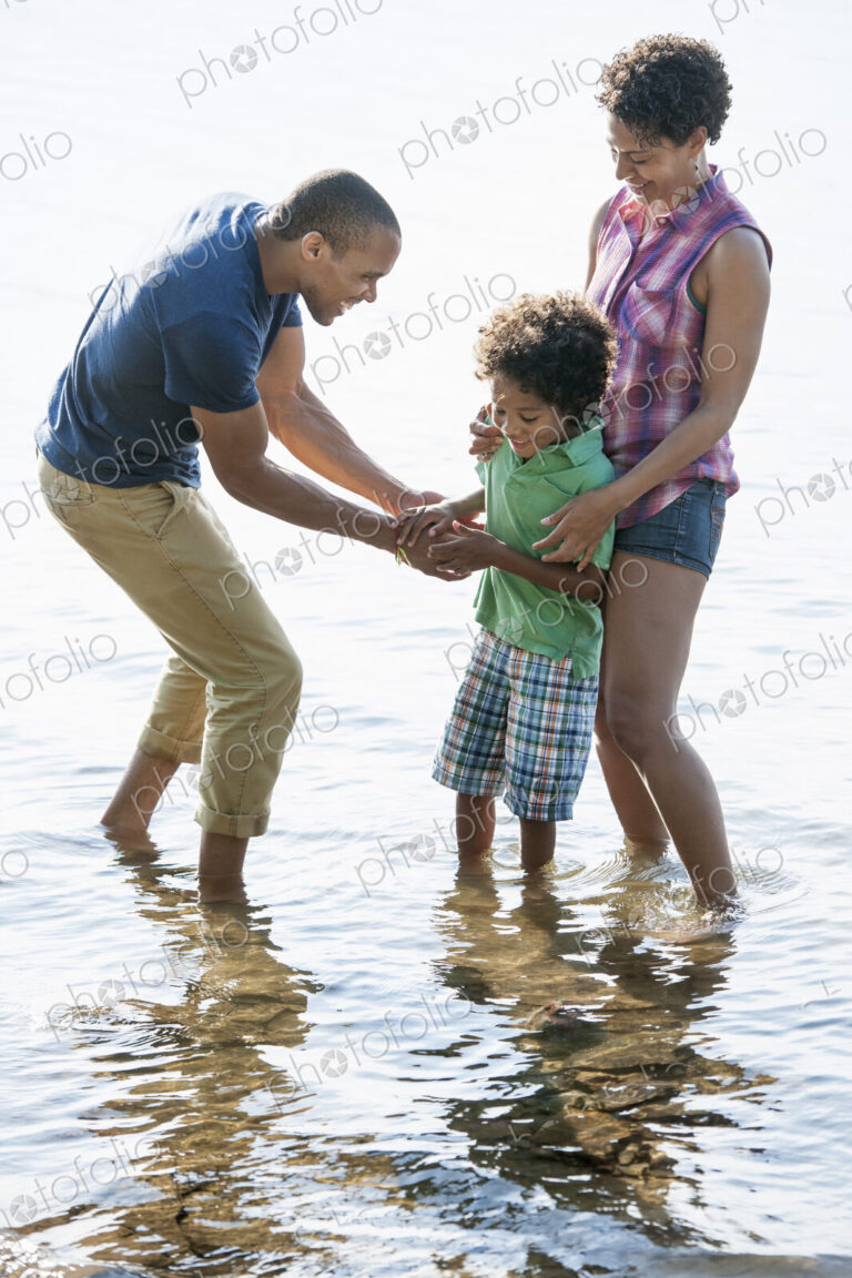 A family, mother, father and son playing on the shores of a lake.