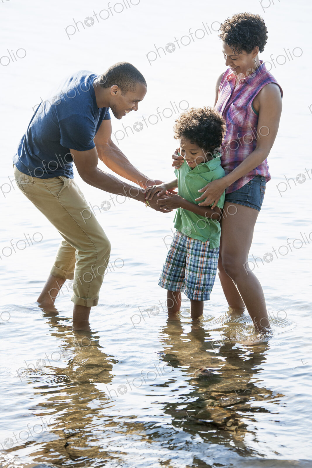 A family, mother, father and son playing on the shores of a lake.