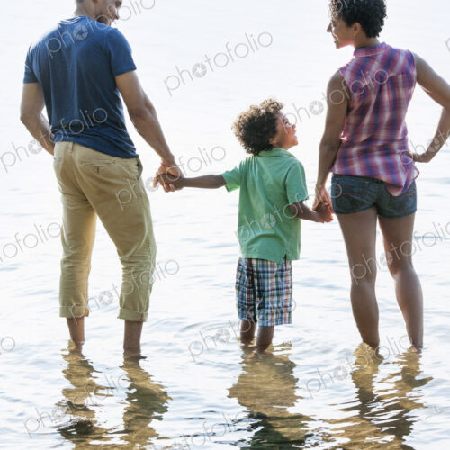 A family, mother, father and son playing on the shores of a lake.