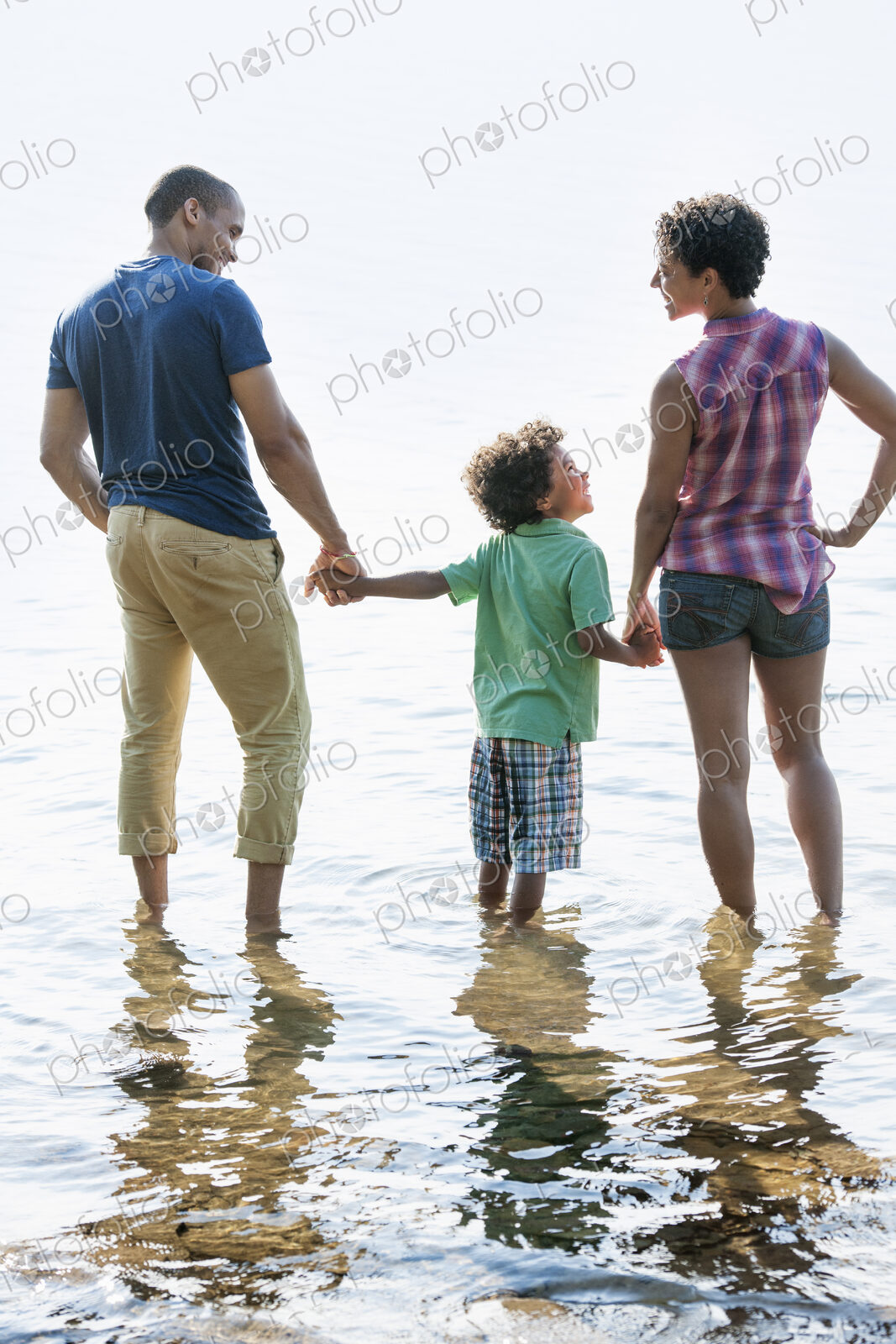 A family, mother, father and son playing on the shores of a lake.