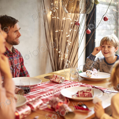 A family of four people at a Christmas meal, pulling crackers A family of four people at a Christmas meal, pulling crackers
