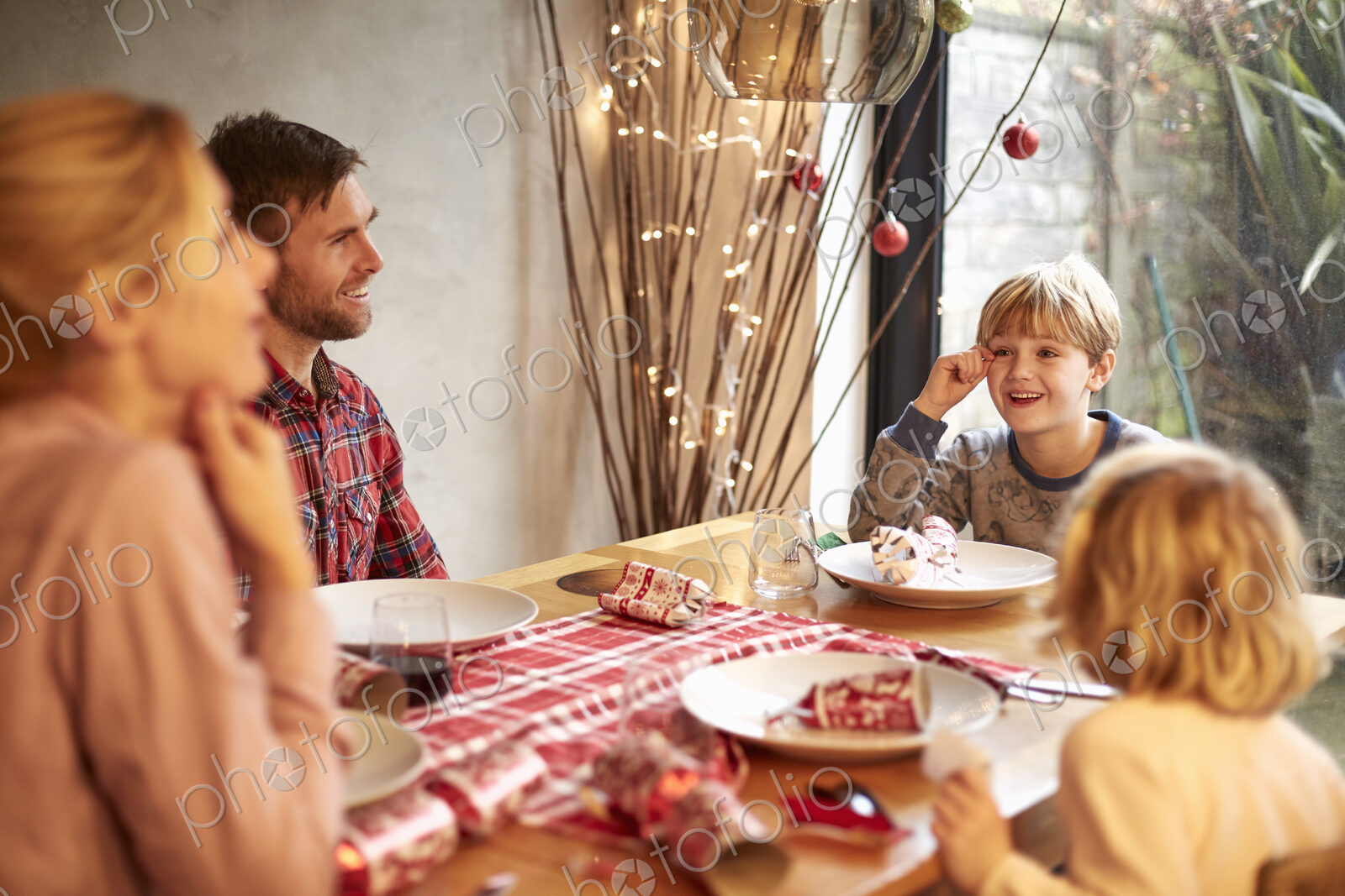 A family of four people at a Christmas meal, pulling crackers