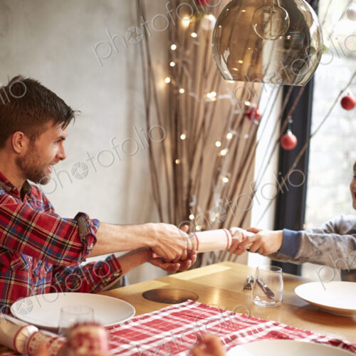 A family of four people at a table at Christmas, pulling crackers. A family of four people at a table at Christmas, pulling crackers.