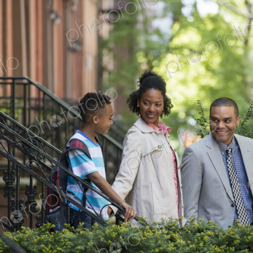 A family outdoors in the city. Two parents and a young boy walking together.