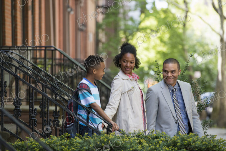 A family outdoors in the city. Two parents and a young boy walking together.