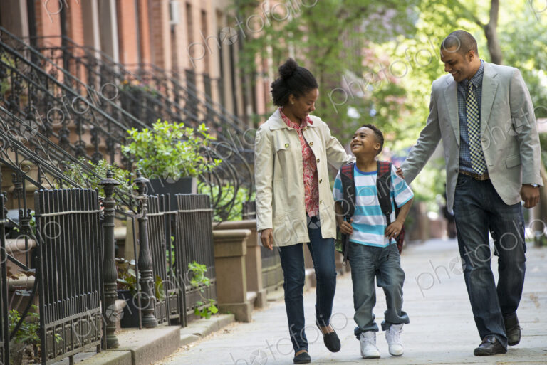 A family outdoors in the city. Two parents and a young boy walking together.