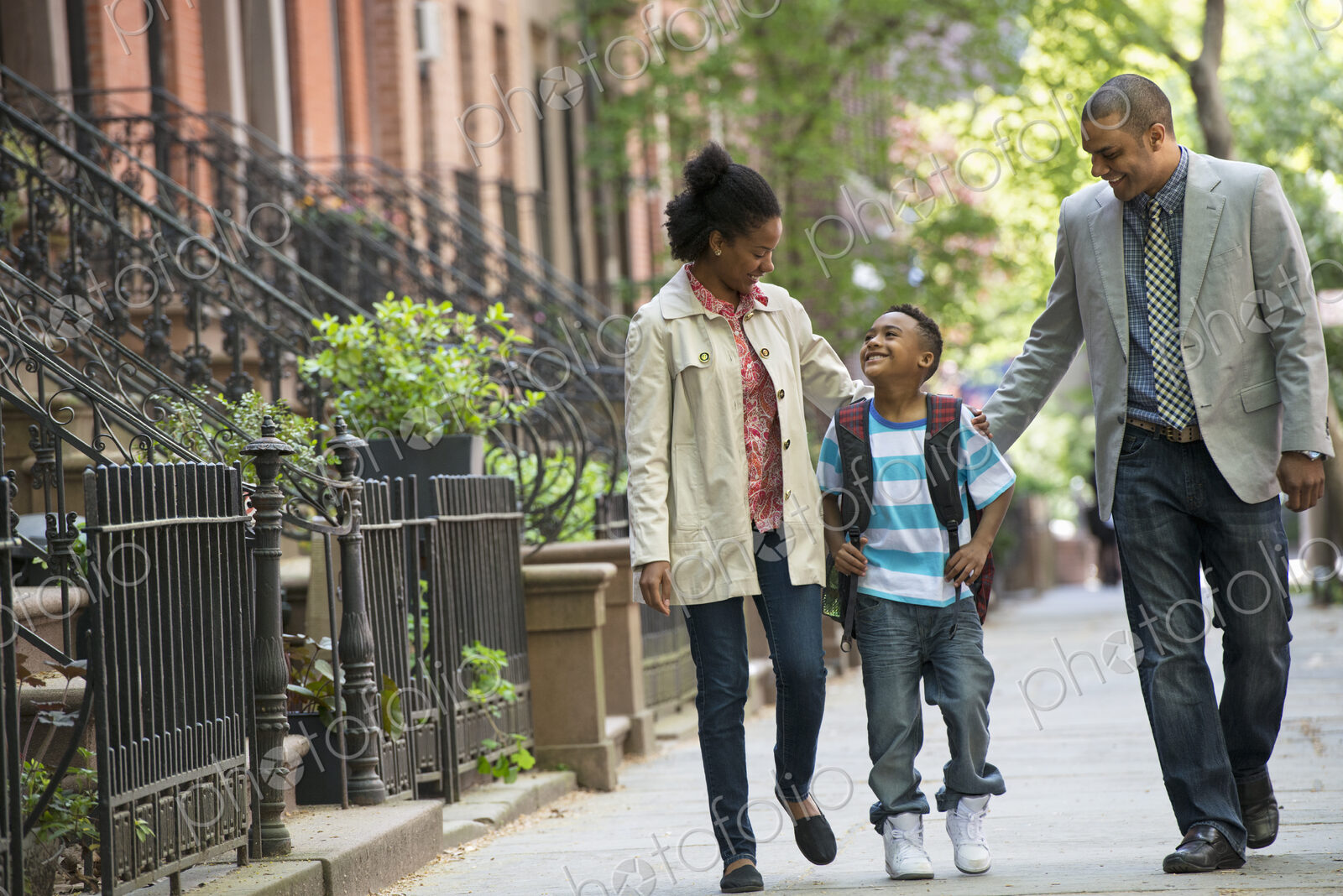 A family outdoors in the city. Two parents and a young boy walking together.