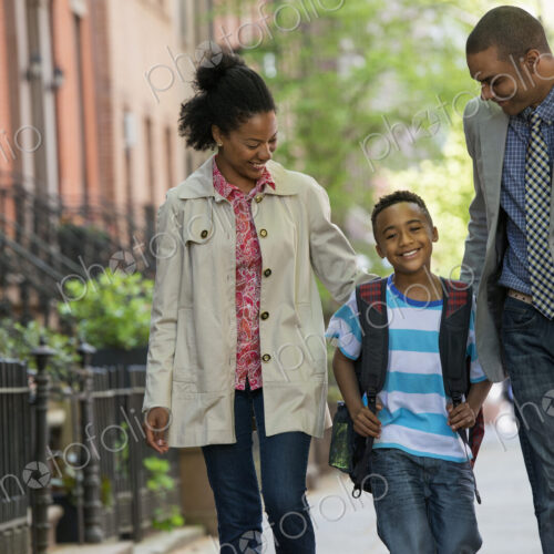 A family outdoors in the city. Two parents and a young boy walking together.