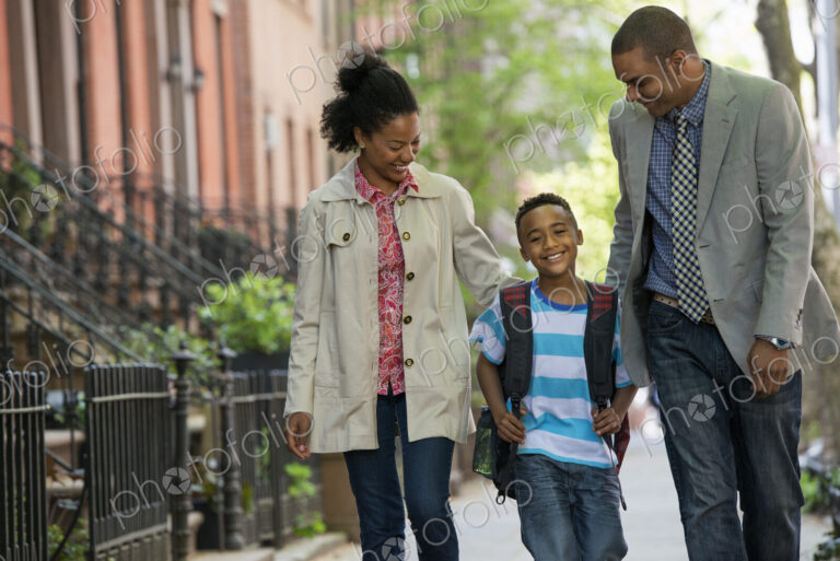 A family outdoors in the city. Two parents and a young boy walking together.