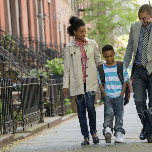 A family outdoors in the city. Two parents and a young boy walking together.