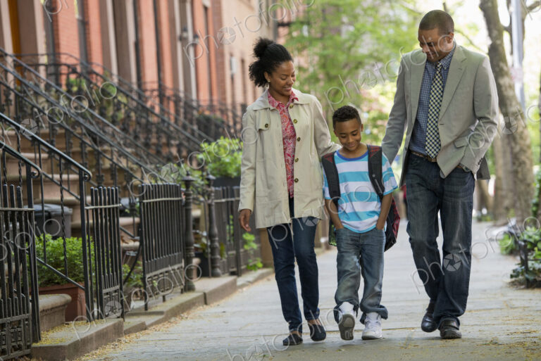 A family outdoors in the city. Two parents and a young boy walking together.