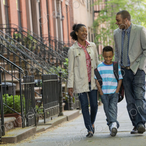 A family outdoors in the city. Two parents and a young boy walking together.