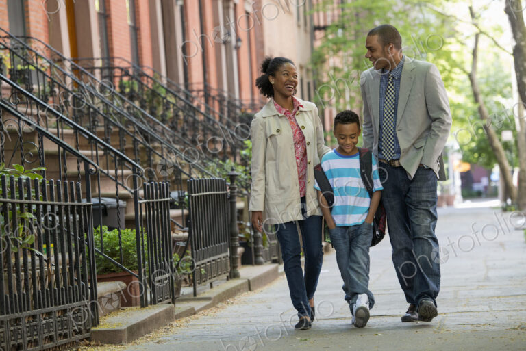 A family outdoors in the city. Two parents and a young boy walking together.