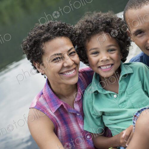 A family, parents and a young boy, by a lake in summer.
