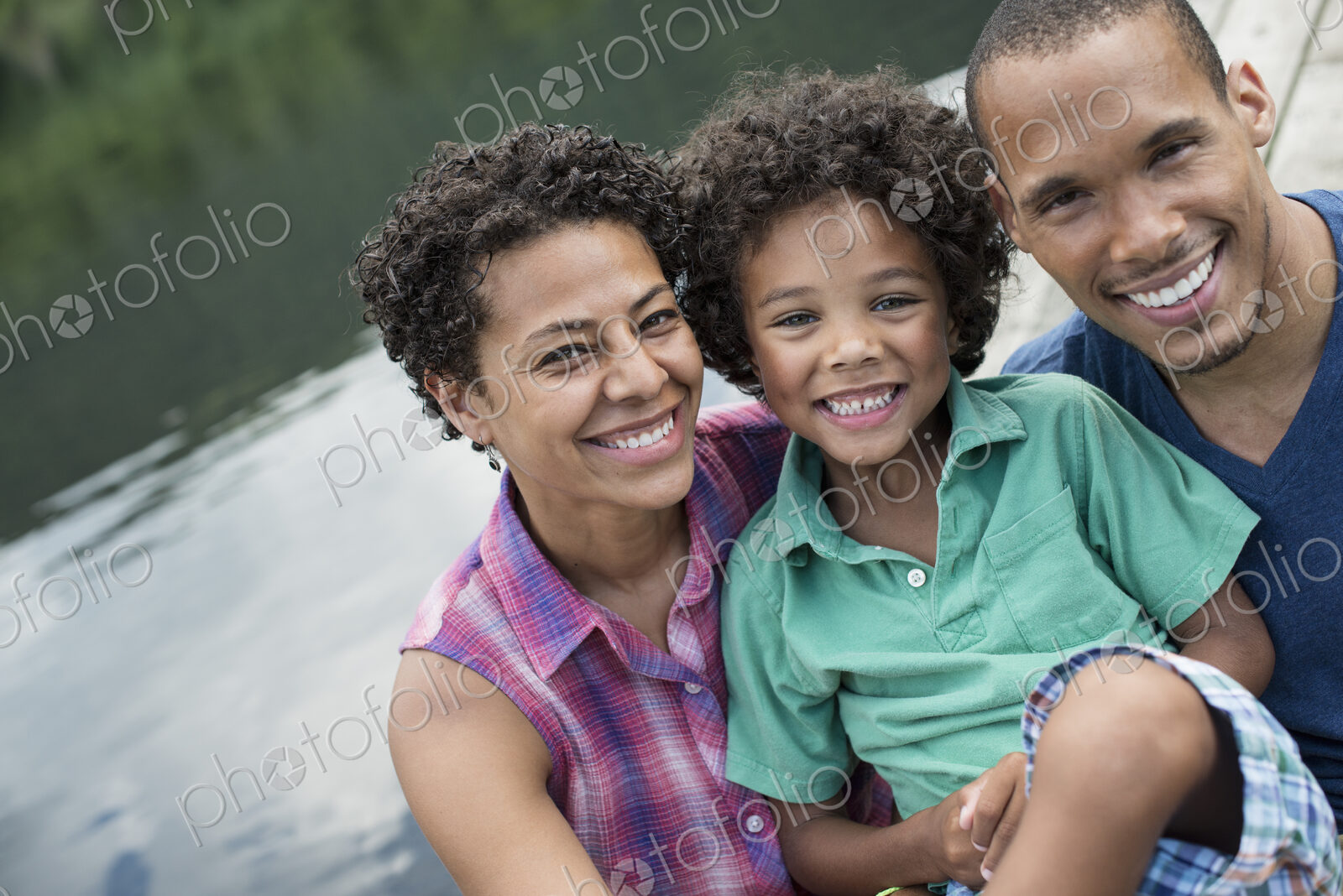 A family, parents and a young boy, by a lake in summer.