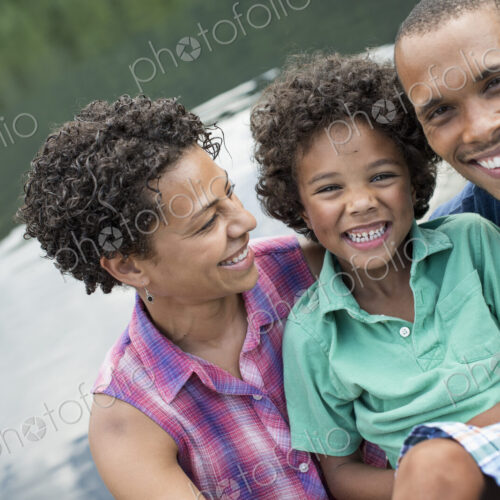 A family, parents and a young boy, by a lake in summer.