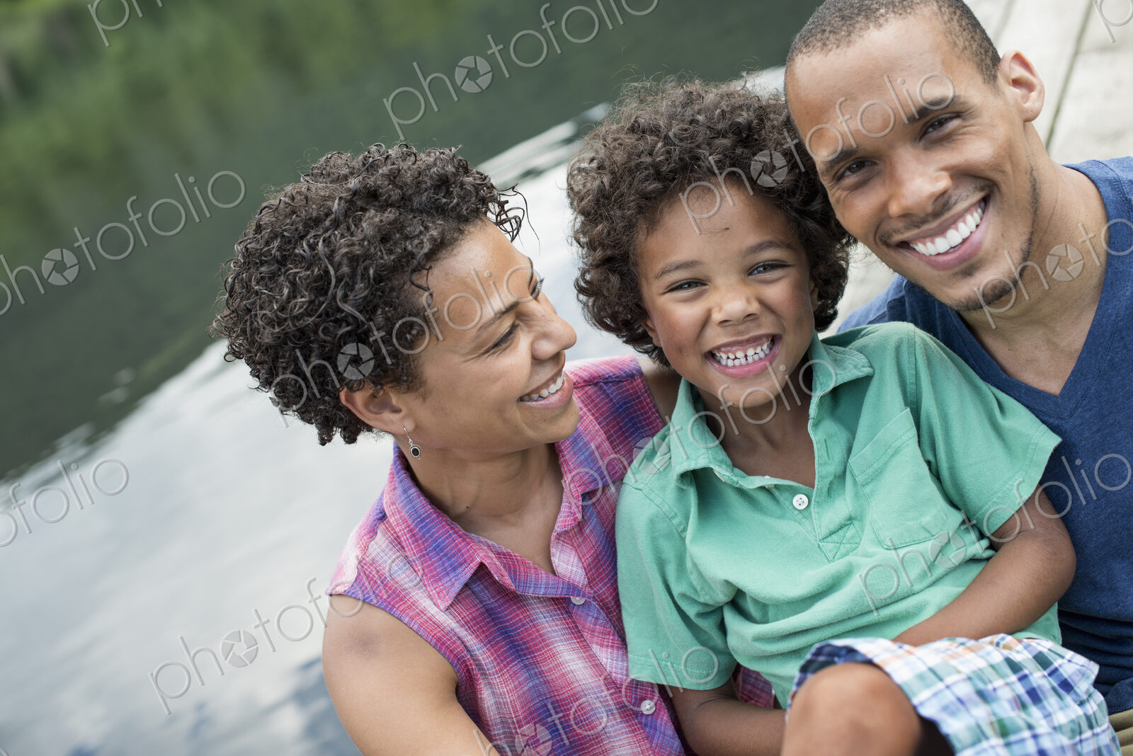 A family, parents and a young boy, by a lake in summer.