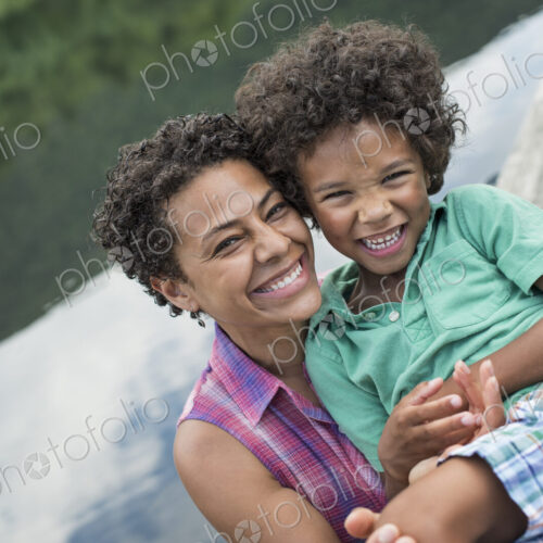 A family, parents and a young boy, by a lake in summer.
