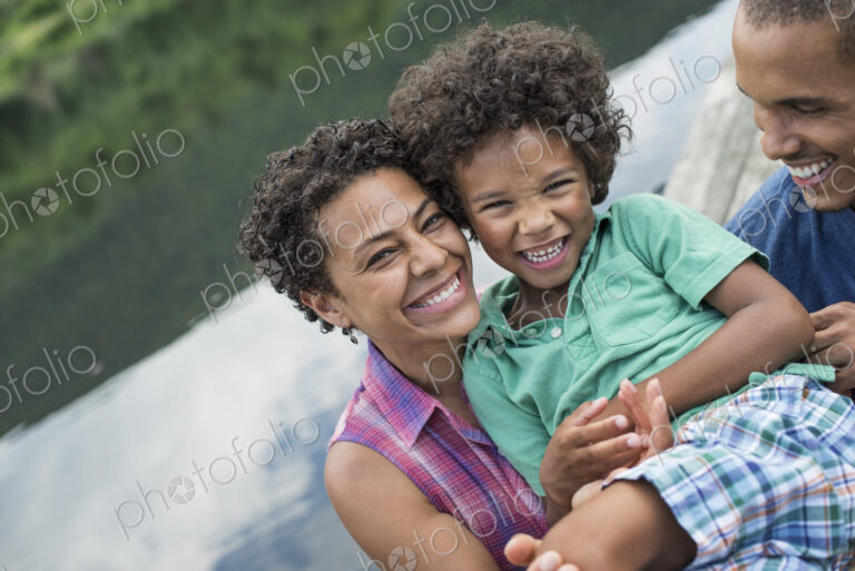 A family, parents and a young boy, by a lake in summer.