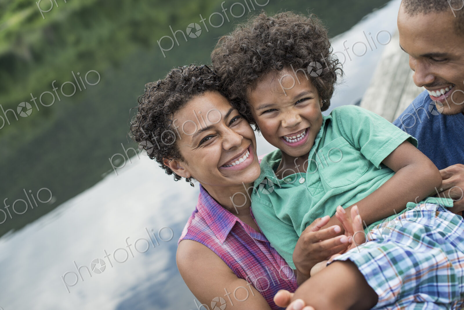 A family, parents and a young boy, by a lake in summer.