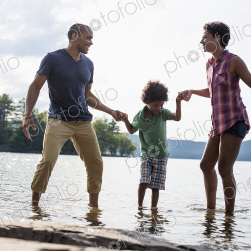 A family, parents and son spending time together by a lake in summer.
