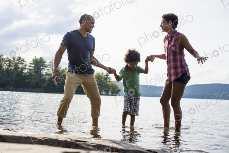 A family, parents and son spending time together by a lake in summer.
