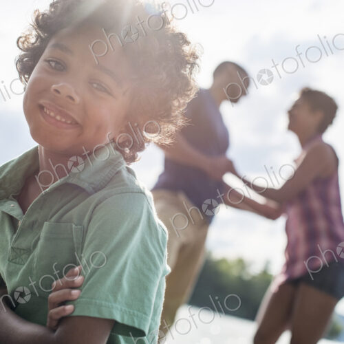 A family, parents and son spending time together by a lake in summer.