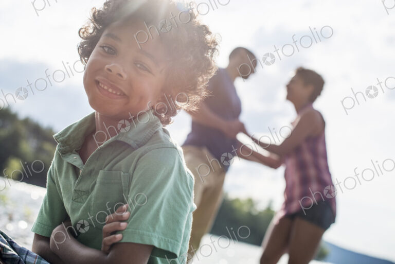 A family, parents and son spending time together by a lake in summer.