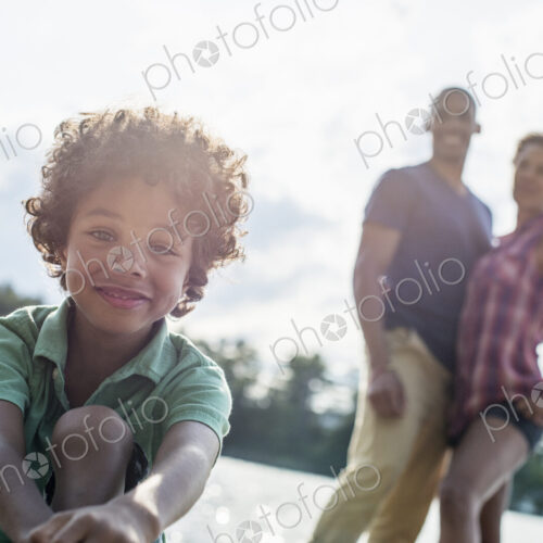 A family, parents and son spending time together by a lake in summer. A family, parents and son spending time together by a lake in summer.