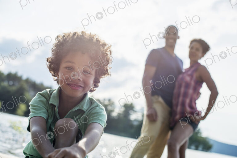 A family, parents and son spending time together by a lake in summer.