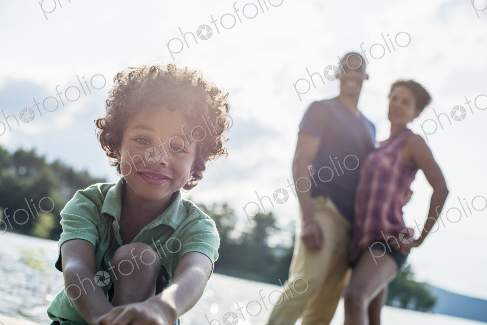 A family, parents and son spending time together by a lake in summer.