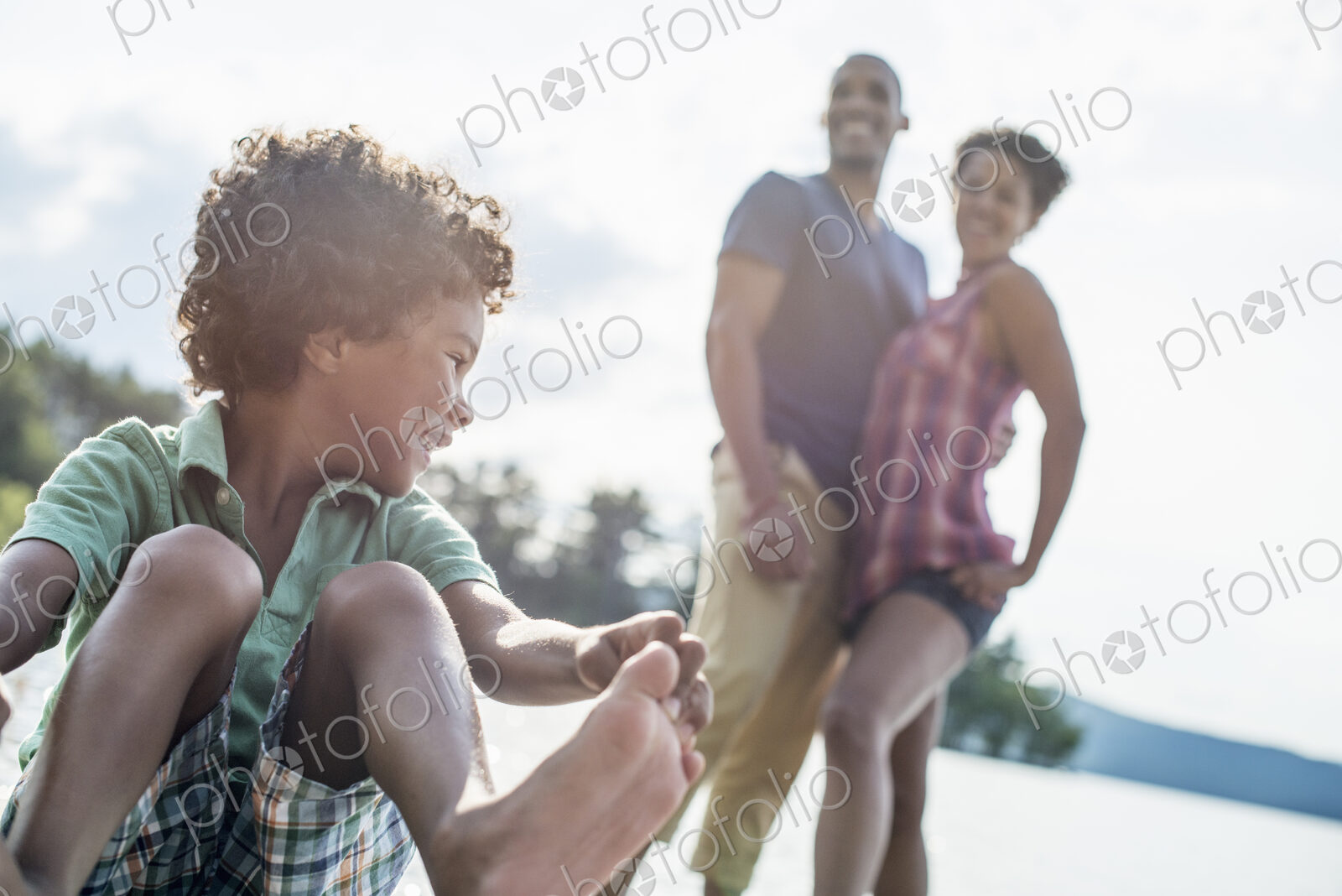 A family, parents and son spending time together by a lake in summer.