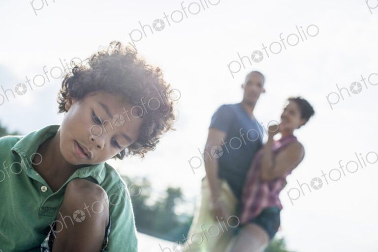 A family, parents and son spending time together by a lake in summer.