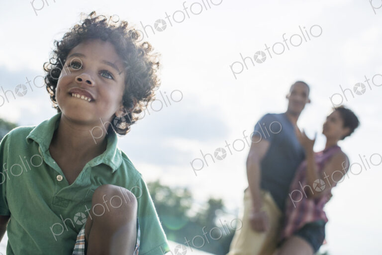A family, parents and son spending time together by a lake in summer.