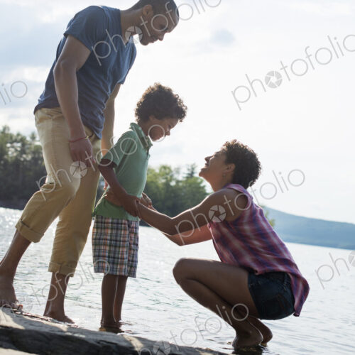 A family, parents and son spending time together by a lake in summer. A family, parents and son spending time together by a lake in summer.
