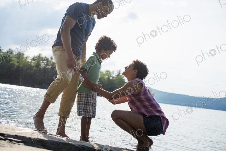 A family, parents and son spending time together by a lake in summer.