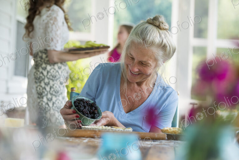 A family party in a farmhouse in the country in New York State. A mature woman holding…