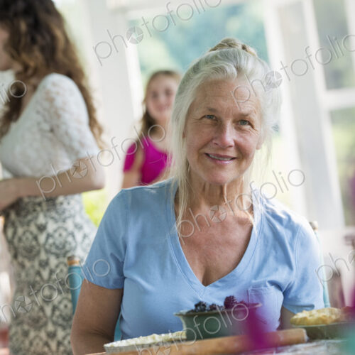 A family party in a farmhouse in the country in New York State. A mature woman holding…