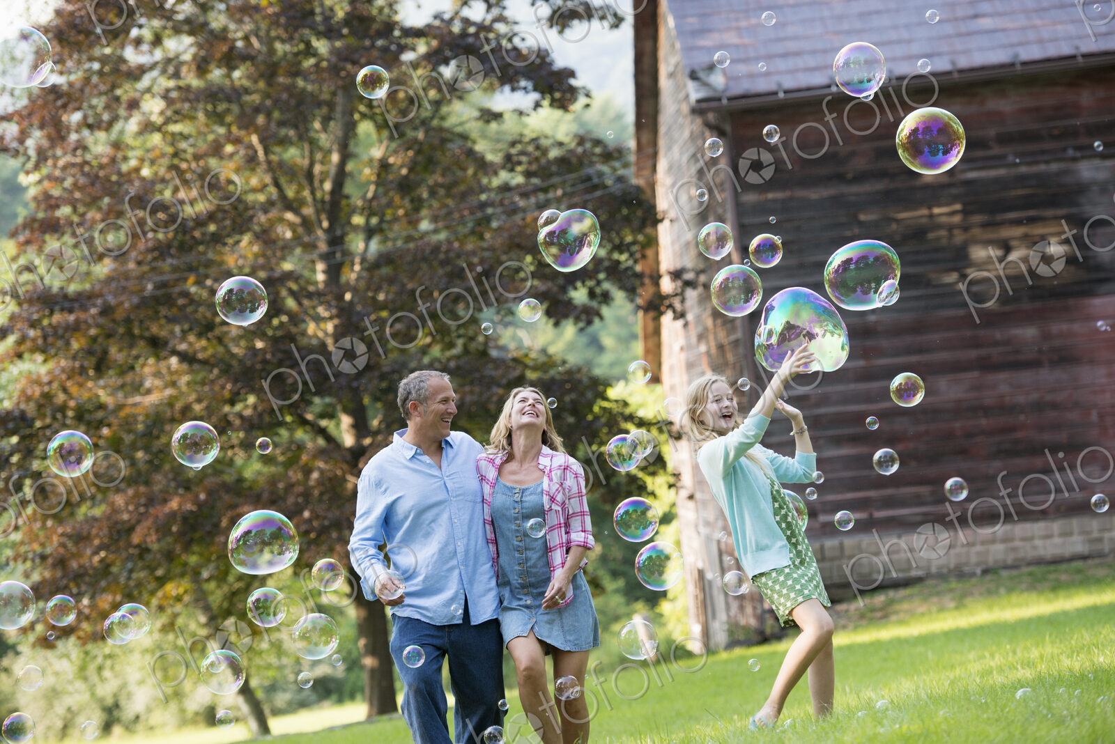 A family sitting on the grass outside a bar, blowing bubbles and laughing.
