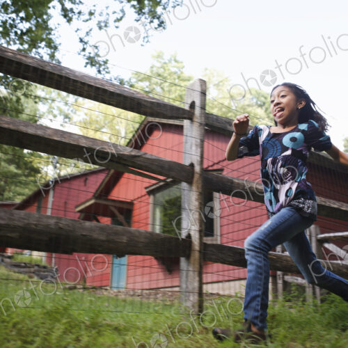 A farm paddock fence. A young girl running around. A farm paddock fence. A young girl running around.