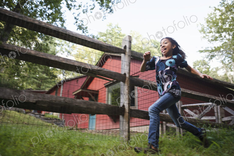 A farm paddock fence. A young girl running around.