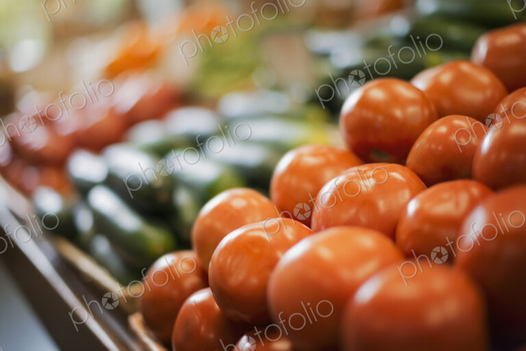 A farm stand display of fresh produce. Tomatoes and cucumbers.