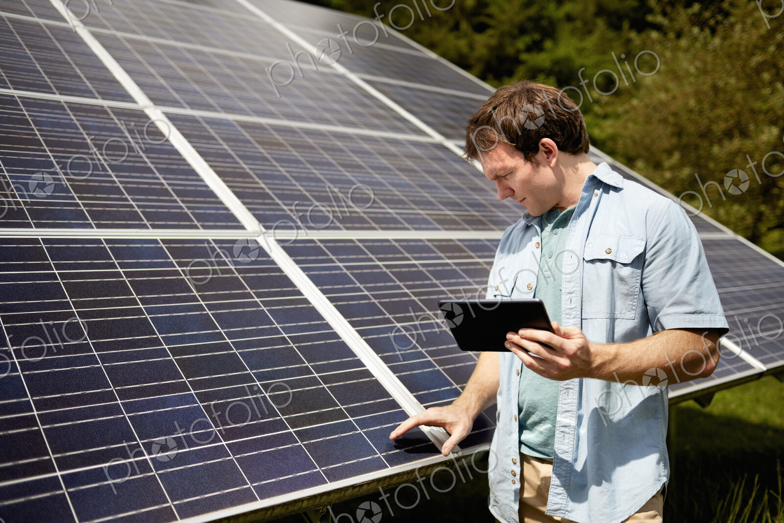 A farmer closely inspecting the surface of a solar panel on the farm.
