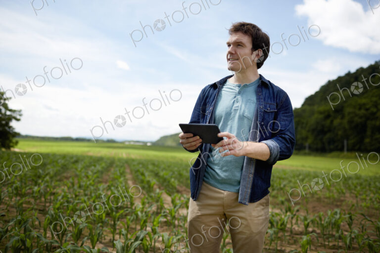A farmer holding a digital tablet, technology in farming, in his fields in New York…