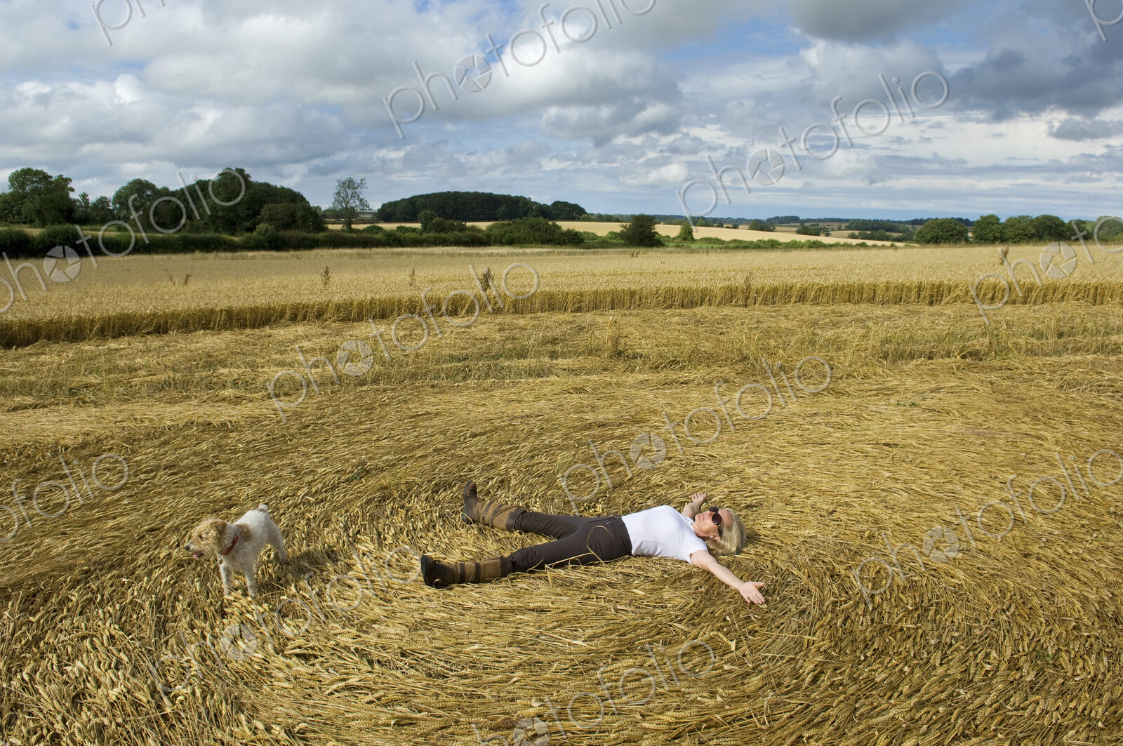 A farmer lying down on his back in the stubble of a freshly cut crop field with arms…
