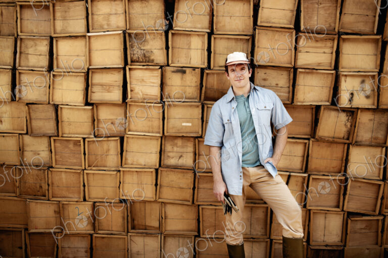 A farmer standing in front of a wall of stacked wooden crates for produce.