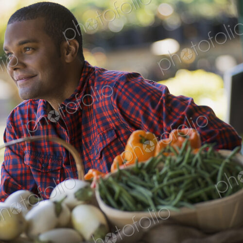 A farmer with a tray of organic bell peppers, green beans and eggplant freshly… A farmer with a tray of organic bell peppers, green beans and eggplant freshly…