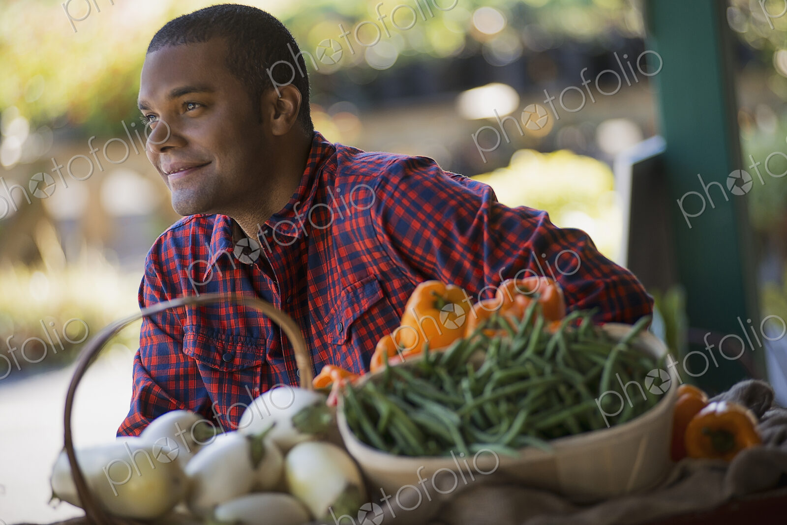 A farmer with a tray of organic bell peppers, green beans and eggplant freshly…