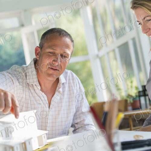 A farmhouse kitchen. A model of a house on the table. Designing a house. A couple.