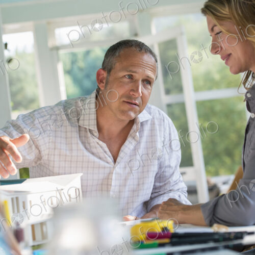 A farmhouse kitchen. A model of a house on the table. Designing a house. A couple.